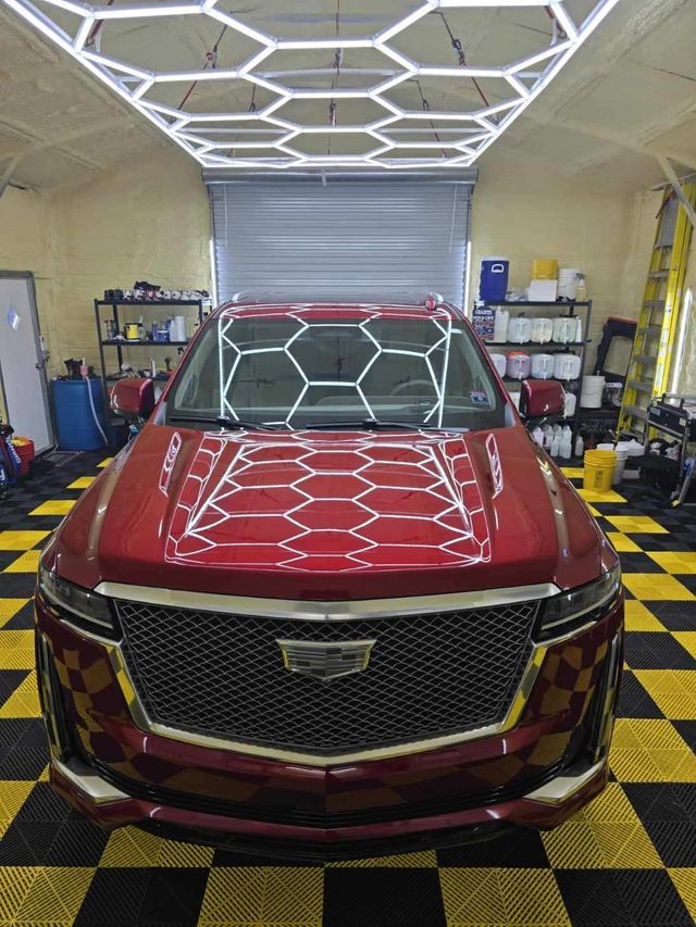 A man in a yellow hat is cleaning a car with a cloth.