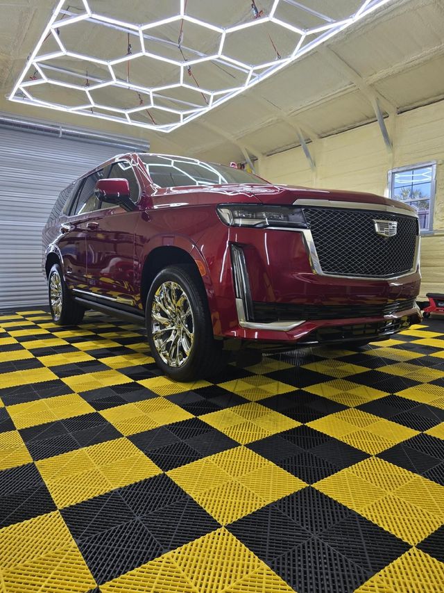 A red cadillac is parked in a garage on a checkered floor.