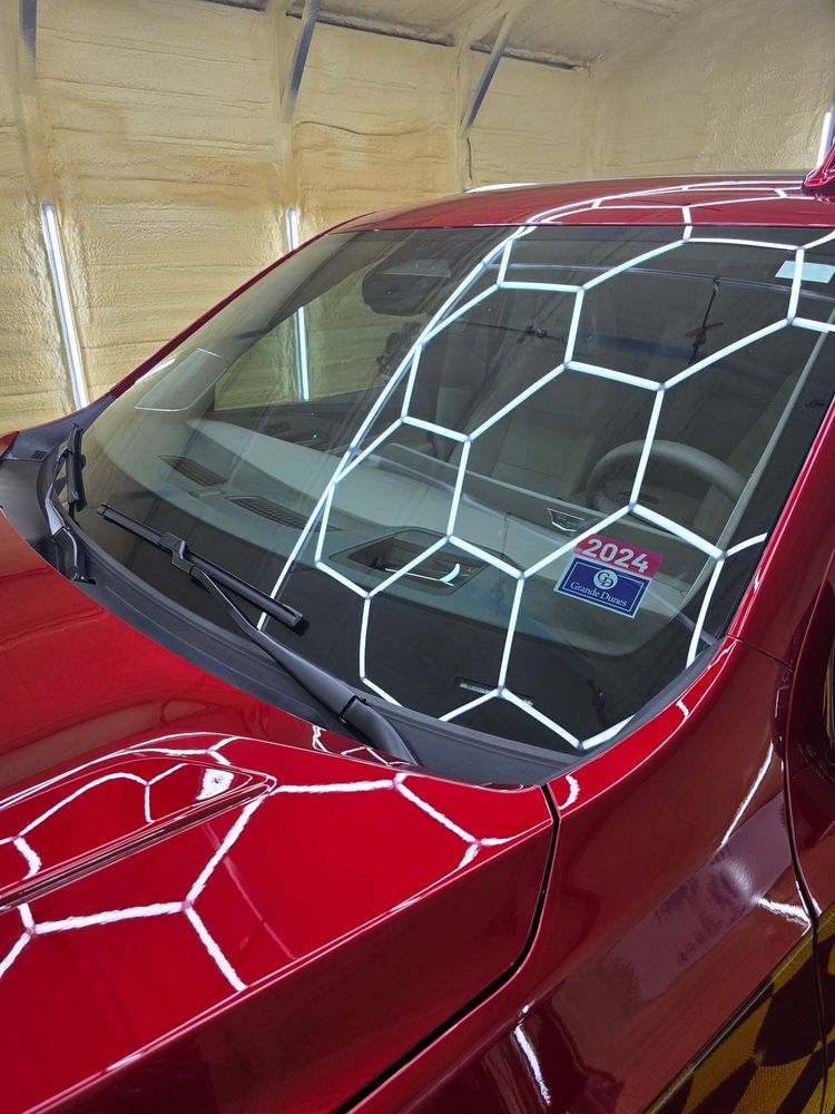 A red car with a sticker on the windshield that says 50724