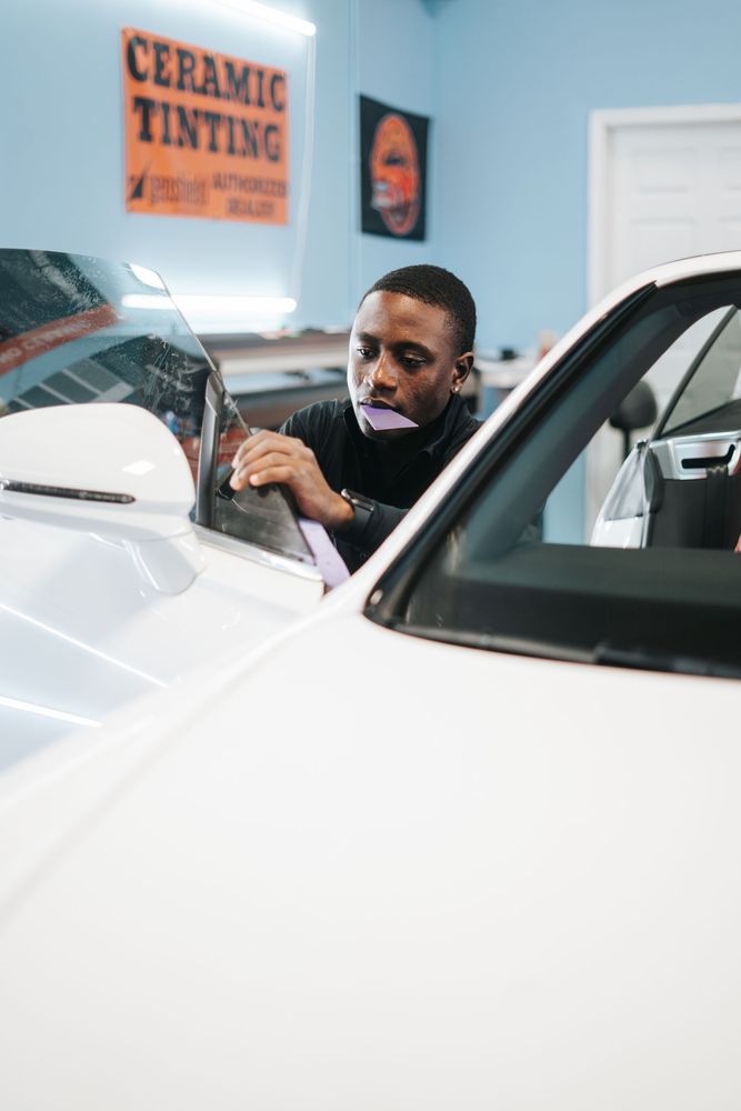 A man is applying ceramic tinting to a car window.