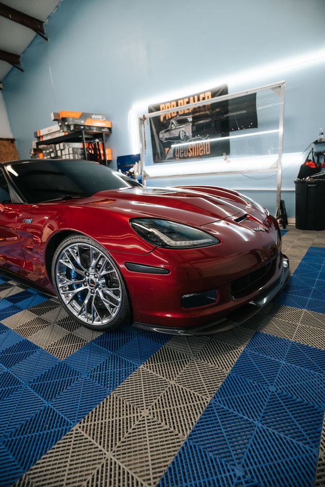A man is working on a red car in a garage.