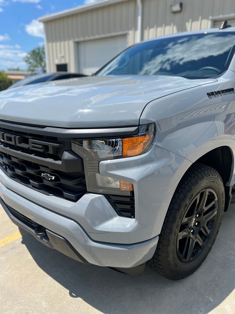 A silver truck is parked in front of a building.